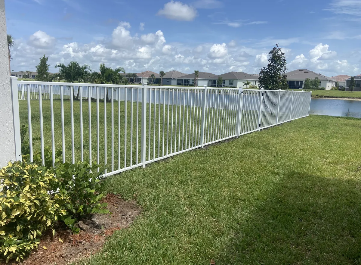 White aluminum fence installed along a residential backyard lake